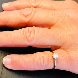 Puede incluir: Un anillo de plata sencillo con un solo diamante redondo.