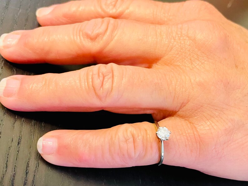 Puede incluir: Un anillo de plata sencillo con un solo diamante redondo.