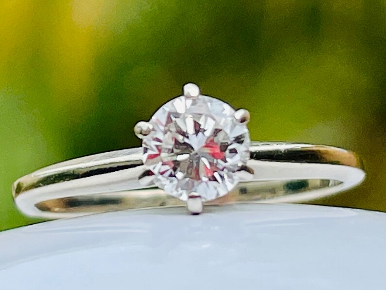 Puede incluir: Un anillo de plata con un solo diamante redondo y transparente.