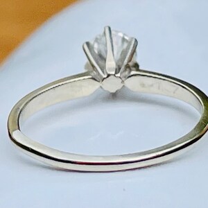 Puede incluir: Un anillo de plata con un solo diamante redondo engastado en garras. El anillo es simple y elegante.