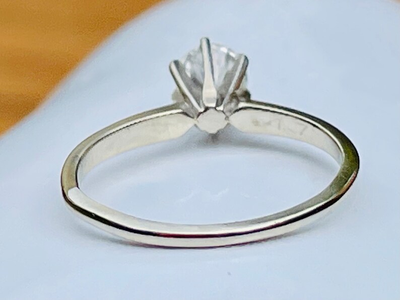 Puede incluir: Un anillo de plata con un solo diamante redondo engastado en garras. El anillo es simple y elegante.