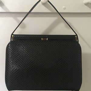 May include: A black leather handbag with a snakeskin pattern and a gold clasp.