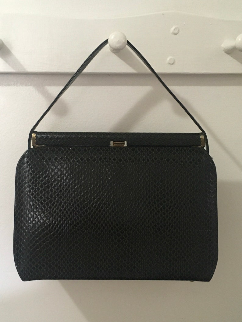 May include: A black leather handbag with a snakeskin pattern and a gold clasp.