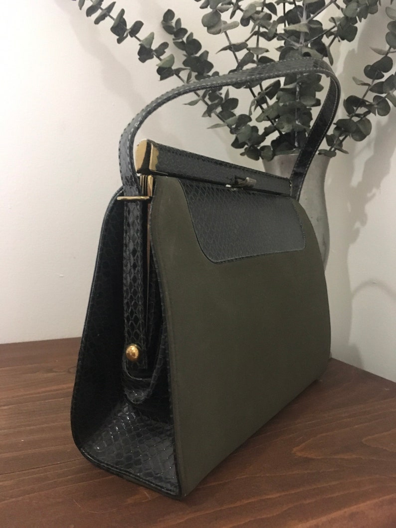 May include: A vintage green and black handbag with a snakeskin pattern and a gold clasp.
