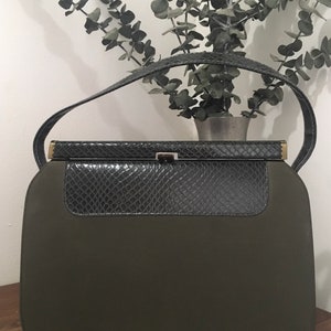 May include: A dark green handbag with a snakeskin flap and a gold clasp.