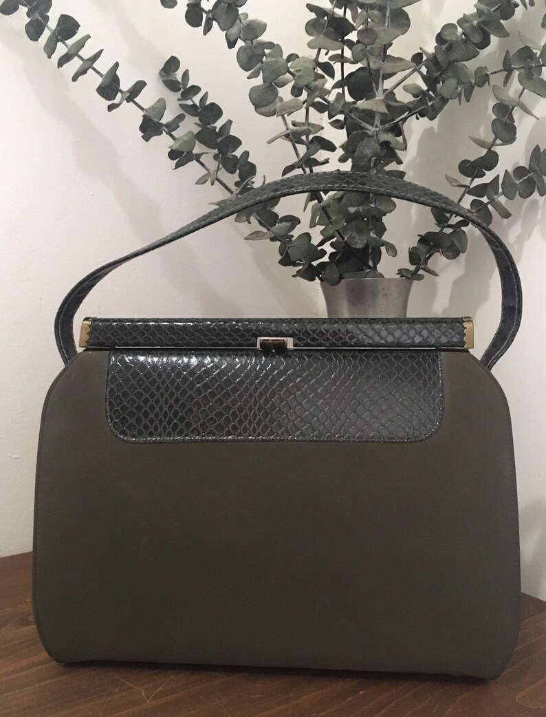 May include: A dark green handbag with a snakeskin flap and a gold clasp.