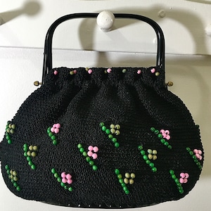 May include: A black crocheted handbag with a black handle and pink and green beaded embellishments.