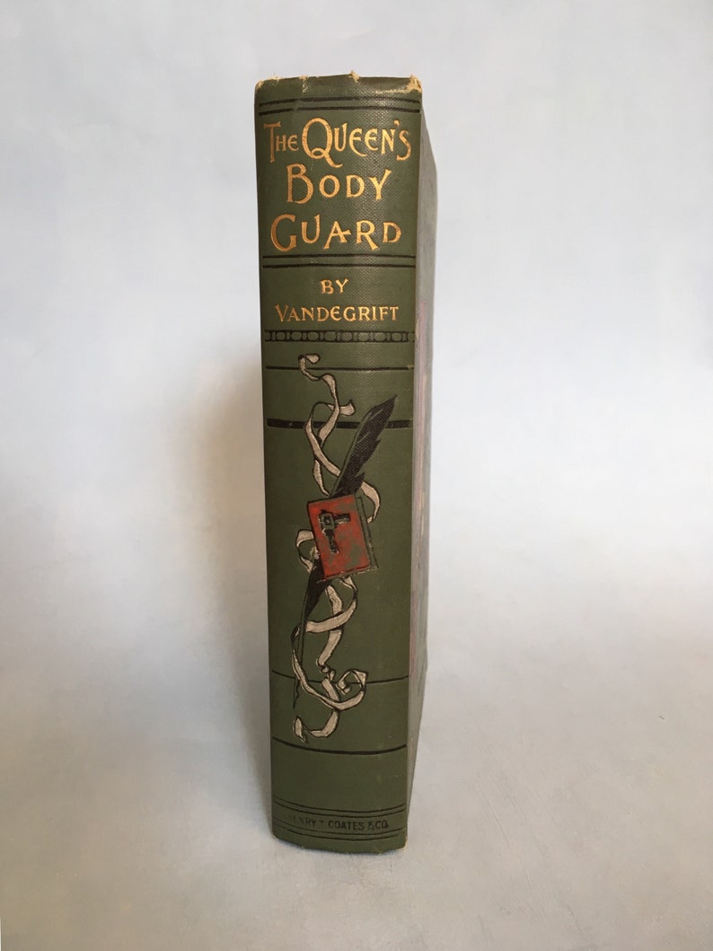 May include: A vintage book titled "The Queen's Body Guard" by Vandegrift. The book's spine is a muted green with gold lettering. A decorative illustration of a quill, ribbon, and a red emblem adorns the spine. The book is published by Henry T. Coates & Co.