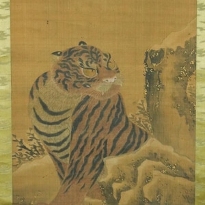May include: A vintage Japanese scroll painting featuring a tiger in a snowy landscape. The tiger has orange and black stripes. The artwork is framed with a gold border and has a tree branch in the upper portion.