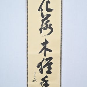 May include: A traditional Japanese calligraphy scroll featuring black ink on a beige background. The characters are written vertically and read "光陰矢のごとし" which translates to "Time flies like an arrow".