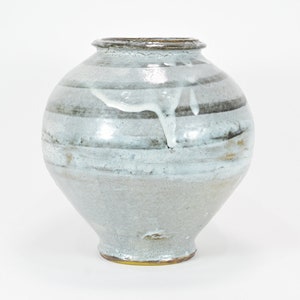 May include: A white ceramic vase with brown and gray glaze. The vase has a round body and a wide mouth.