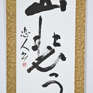 May include: A black and white Japanese calligraphy scroll featuring the characters "心" and "空" written in bold strokes. The scroll is mounted on a gold background with a floral pattern.
