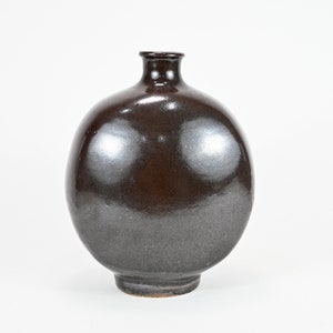 May include: A dark brown ceramic vase with a round body and a narrow neck. The vase has a glossy finish.