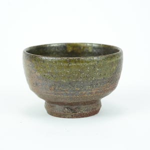 May include: A handcrafted ceramic bowl with a textured surface. The bowl features a gradient of colors, transitioning from a dark green rim to a brown base. The bowl is approximately 4 inches in diameter and 3 inches tall.