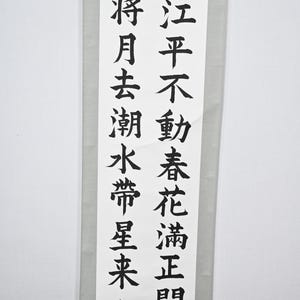 Peut inclure: Un rouleau vertical avec calligraphie noire sur papier blanc. Le texte est composé de caractères chinois et est encadré par un bord gris clair. Une œuvre d'art traditionnelle.
