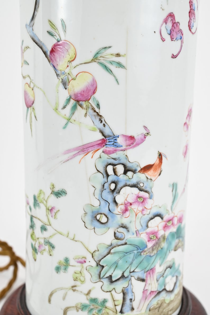 K&ouml;nnte beinhalten: Eine wei&szlig;e Porzellan-Lampenbasis mit einem floralen und Vogel-Design. Die Basis zeigt einen rosa und gelben Pfirsichbaum mit einem blauen und rosa Vogel, der auf einem Ast sitzt. Die Basis ist mit gr&uuml;nen Bl&auml;ttern und rosa Bl&uuml;ten verziert.