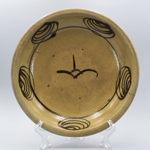May include: A yellow ceramic plate with a black swirl design around the rim. The plate has a black swirl design in the center.