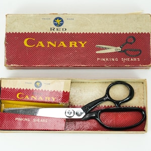 May include: Vintage Canary pinking shears in their original box. The box is red and cream with the words "Canary" and "Pinking Shears" printed on it. The shears have black handles and silver blades.