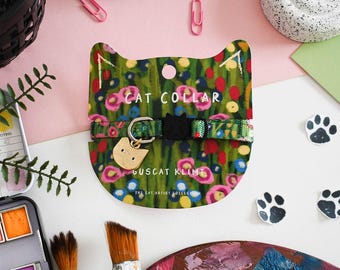 May include: A green cat collar with a gold cat charm and a colourful floral pattern. The collar is labelled "Guscat Klimt" and "The Cat Artist Collection".