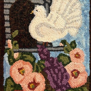 May include: A rug hooking depicting a white dove with its wings spread, perched on a windowsill with purple flowers and green leaves. The dove is against a blue sky background.