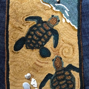 May include: A hand-hooked rug depicting two sea turtles swimming in the ocean. The rug has a beige background with a blue and white wave pattern. The turtles are brown and green with detailed shells.
