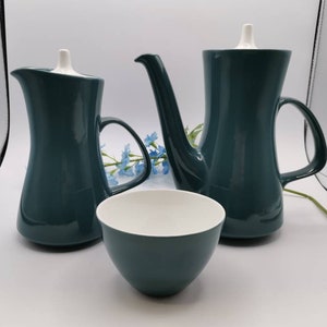 May include: A teal green ceramic tea set with a teapot, creamer, and sugar bowl. The set has a modern design with a white lid on each piece.