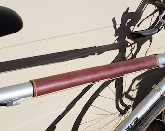 May include: A silver bicycle with a brown leather handlebar wrap. The bicycle has a black seat and a silver frame.