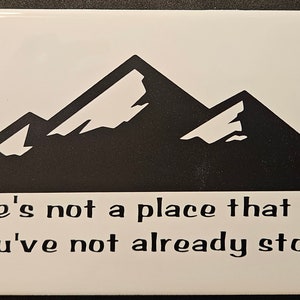 Könnte beinhalten: Eine weiße Keramikfliese mit einer schwarzen Silhouette von Bergen und dem Text "There's not a place that I'll go You've not already stood."