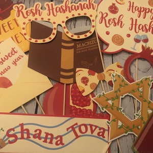 Puede incluir: Accesorios variados para fotomat&oacute;n de Rosh Hashan&aacute; sobre palos de madera. Incluyen gafas, un libro, una granada, una estrella de David y bocadillos con textos como "Happy Rosh Hashanah" y "Shana Tova".