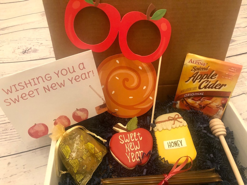 Puede incluir: Una caja de regalo con art&iacute;culos festivos. Incluye una tarjeta que dice "Wishing You a Sweet New Year!", accesorios para fotos con forma de manzana, una piruleta, sidra de manzana, una galleta con forma de miel y un cuchar&oacute;n de miel.
