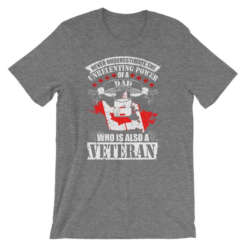 Może przedstawiać: Szara koszulka z grafiką z napisem: "Never Underestimate the Unrelenting Power of a Dad Who Is Also a Veteran". Projekt zawiera flagę Kanady i liście klonu.