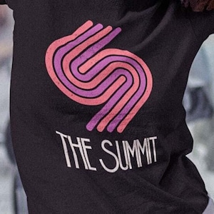 May include: Black t-shirt with a pink and orange graphic of a stylized letter 'S' and the text 'THE SUMMIT'.