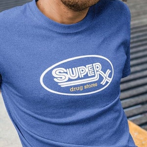 May include: A blue t-shirt with a white retro logo that says "SUPER drug stores" in a white oval.