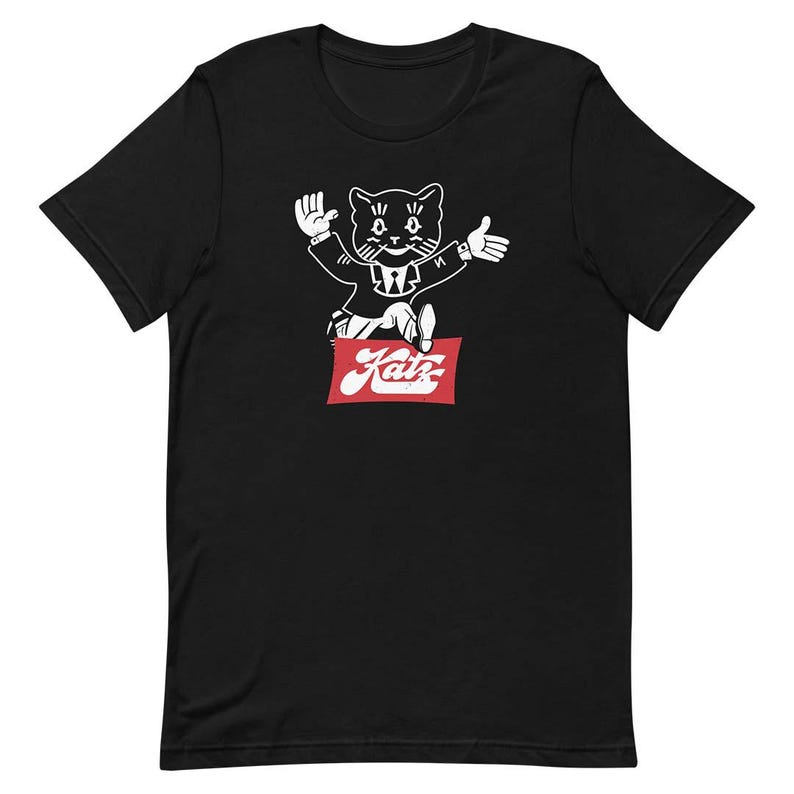 May include: Black t-shirt with a white illustration of a cat wearing a suit and holding a red sign that says "Katz".