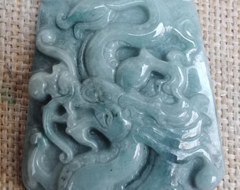 May include: A jade pendant carved with a detailed dragon design. The pendant is a light green color and has a smooth, polished finish.