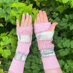 Peut inclure: Mitaines roses et grises avec un design superposé. Les gants présentent des sections en tricot côtelé, en dentelle ajourée et en tissu à motifs. Les poignets et les sections sont de couleur rose uni, tandis que les sections centrales sont grises et à motifs.