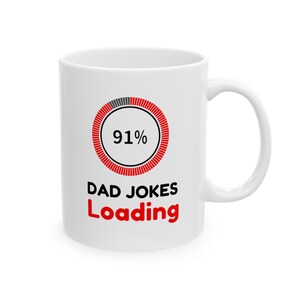 May include: White ceramic mug with a black and red graphic. The graphic includes a loading bar that is 91% complete, with the words "DAD JOKES LOADING" in red and black text. The mug has a curved handle.