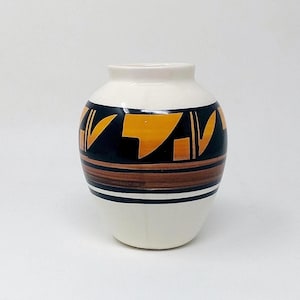May include: A ceramic vase with a rounded body and a short neck. The base color is off-white, featuring a wide horizontal band around the center decorated with black and orange geometric shapes, complemented by thinner brown and black horizontal stripes.