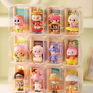 Puede incluir: Una colección de figuras coloridas exhibidas en cajas de plástico transparente. Cada figura tiene un diseño único, con varios personajes y temas. El texto "Sponge" y "LOVE STORY" es visible en las cajas. El texto en la parte inferior dice "Las figuras que se muestran son solo para fines de exhibición y no están a la venta."