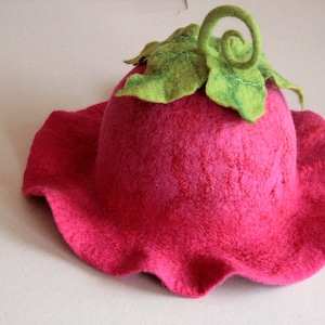 Peut inclure: Un chapeau en feutre rose en forme de fleur avec une tige et des feuilles en feutre vert.