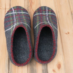May include: A pair of gray wool slippers with a red and green plaid pattern. The slippers have a red stitched trim around the edges.
