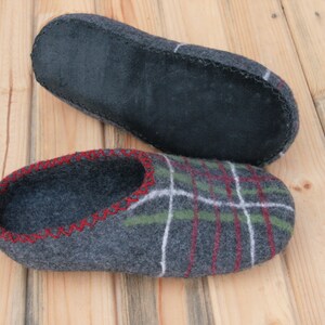 May include: A pair of gray wool slippers with a plaid pattern and red stitching. The slippers have a black leather sole.
