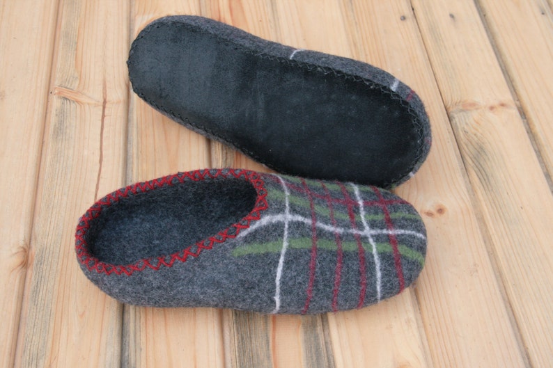 May include: A pair of gray wool slippers with a plaid pattern and red stitching. The slippers have a black leather sole.