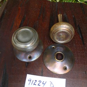 May include: A set of three antique brass door knobs. The knobs are round and have a decorative design. The knobs are in good condition and have a patina finish.