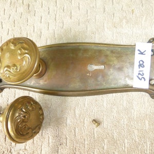 May include: Antique brass door hardware set with a decorative plate, two knobs, and a keyhole. The plate has a label with the text "5212 K".