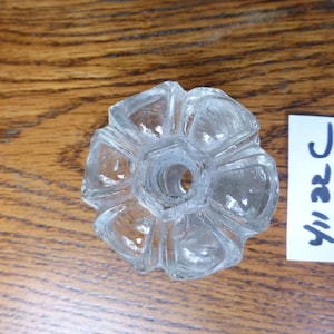 Könnte beinhalten: Ein durchsichtiger Glasflaschenverschluss mit einem Sternmuster. Der Verschluss hat ein zentrales Loch zum Einsetzen in eine Flasche.