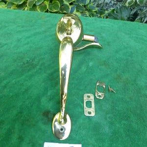May include: Brass door handle with a curved lever and a round knob. The handle is attached to a square plate with two screws. The handle is labeled "4222Y B".