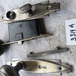 Könnte beinhalten: Ein Vintage-Türbeschlag-Set in Silber mit einem Schlüsselloch und einem runden Knauf. Das Set beinhaltet eine Türplatte, eine Schließplatte, einen Riegel und einen Knauf. Die Beschläge sind in gutem Zustand und haben eine Patina-Oberfläche.