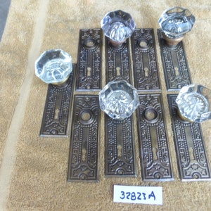 May include: Eight antique door knobs with clear glass and ornate brass plates. The plates have a keyhole and intricate designs. The knobs are arranged in two rows of four on a brown surface. The text "32823 A" is visible in the lower right corner of the image.