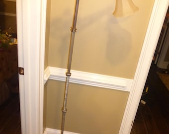 May include: A vintage floor lamp with a decorative metal base and a frosted glass shade. The lamp has a long, slender arm and a geometric design.